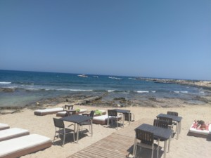 View from the cafe looking out to the sea with sunbeds and tables on a small beach