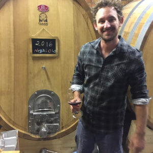 Luke Lambert Australian wine maker standing in front of a big barrel of Wine
