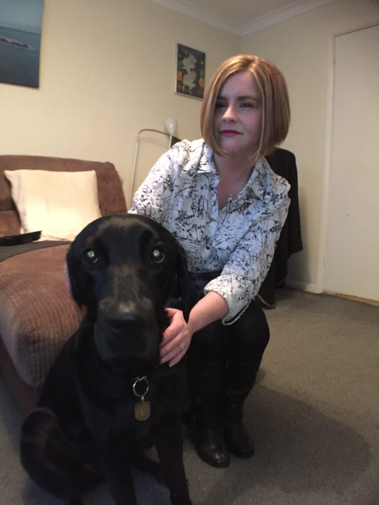 A shot of Sassy sitting on the sofa and ida sat by her feet looking at the camera