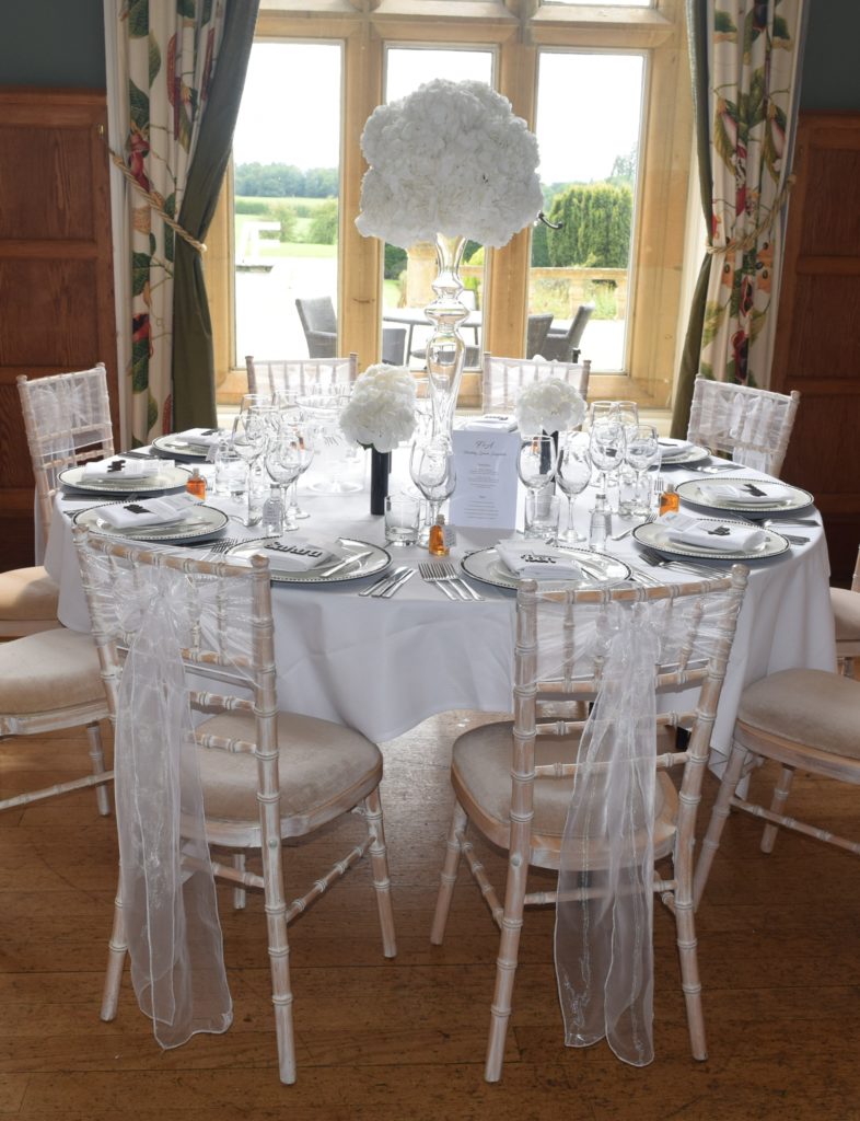A wedding table set up in the red room with a view looking out the window on to the back lawns of the hall