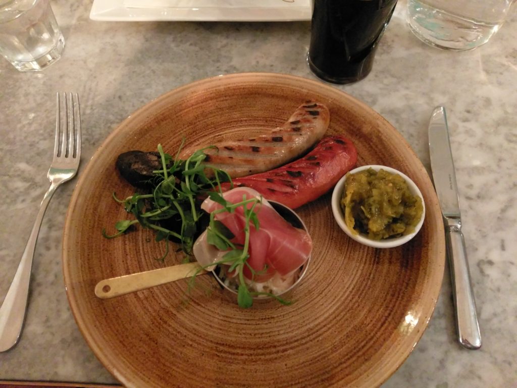 Mix Grilled Saussage on a wooden plate with colesaw in a little saucepan