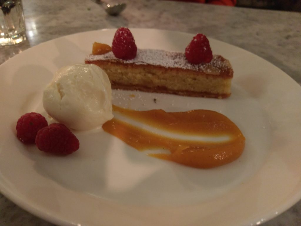 Rasberry dessert on a white plate with ice cream and a mango sauce