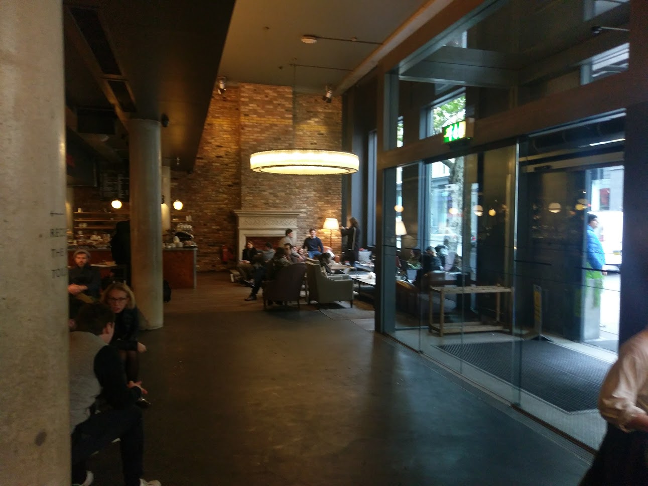 The Hoxton shoreditch lounge area, multiple arm chairs and tables arranged in front of a fireplace.