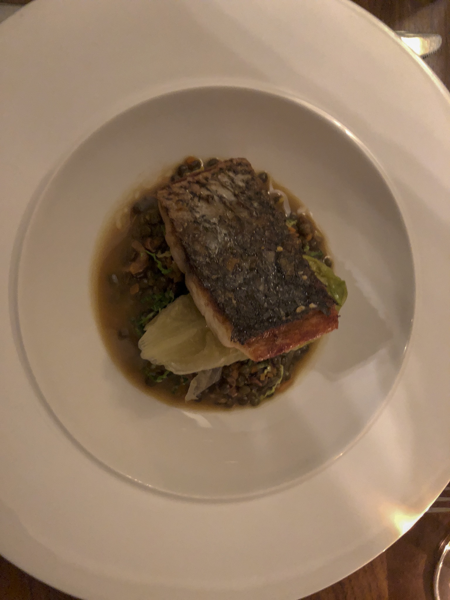 Pan Fried Fillet of Wild Bass sitting onto of puy lentils with savory cabbage