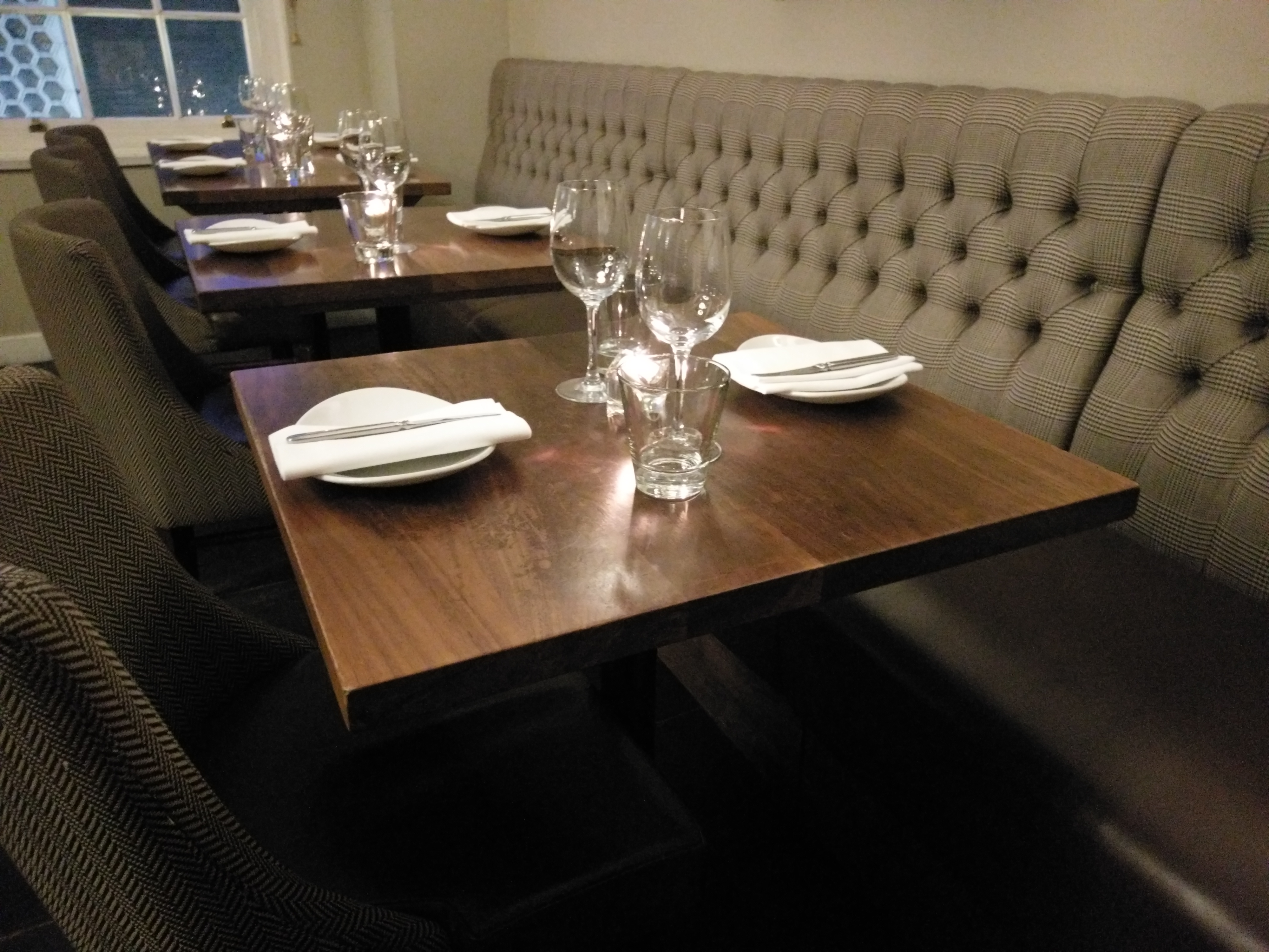 A row of set table s with plates and wine glasses