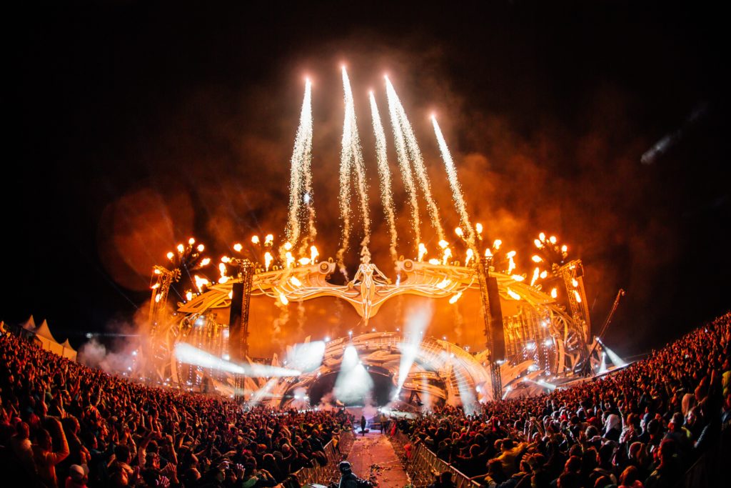 Fireworks shooting up above a stage well light at night.