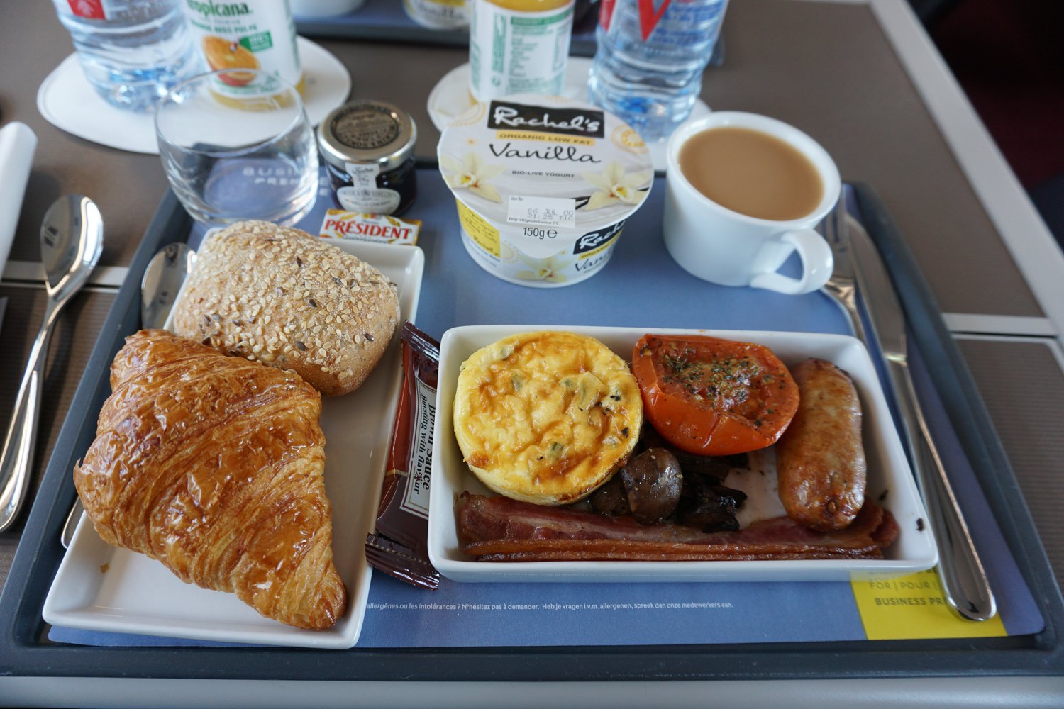English breakfast including croissants, yogurt, bread roll, and cup of tea