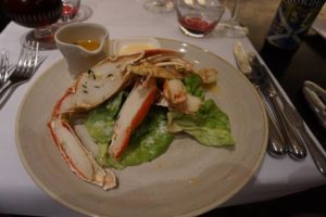 Crab legs and claws on a bed of salad with a melted butter sauce