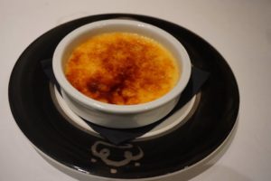 creme brulee in a white dish on a black plate.