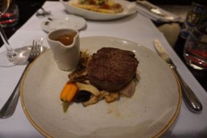 A cut of steak resting on a bed of vegetables