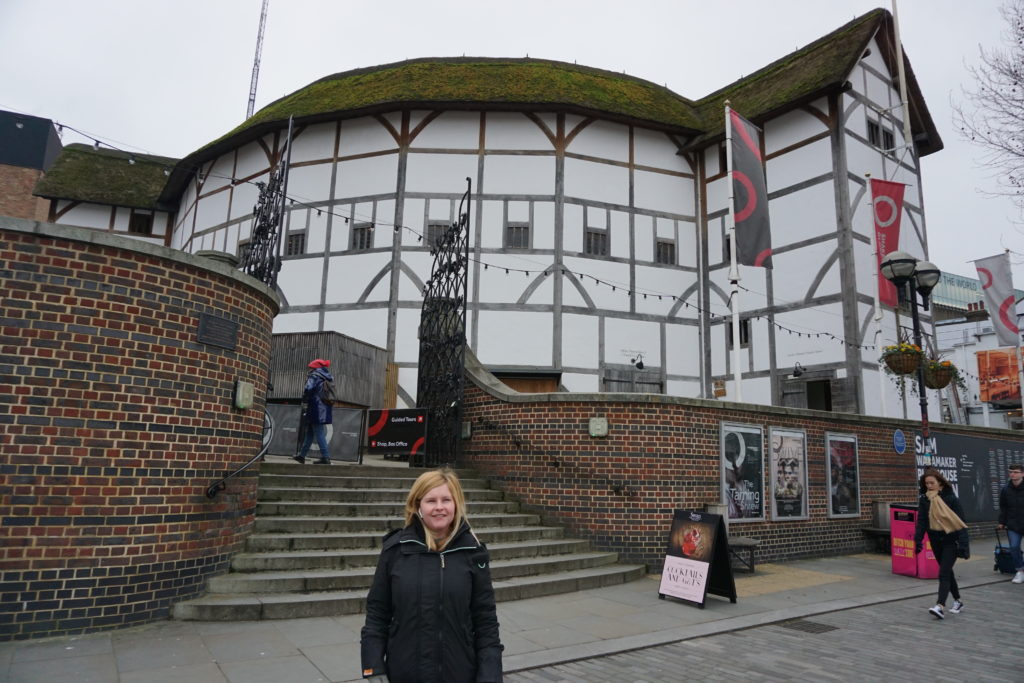 Sassy Standing outside the Globe theatre, the white walls and straw roof.