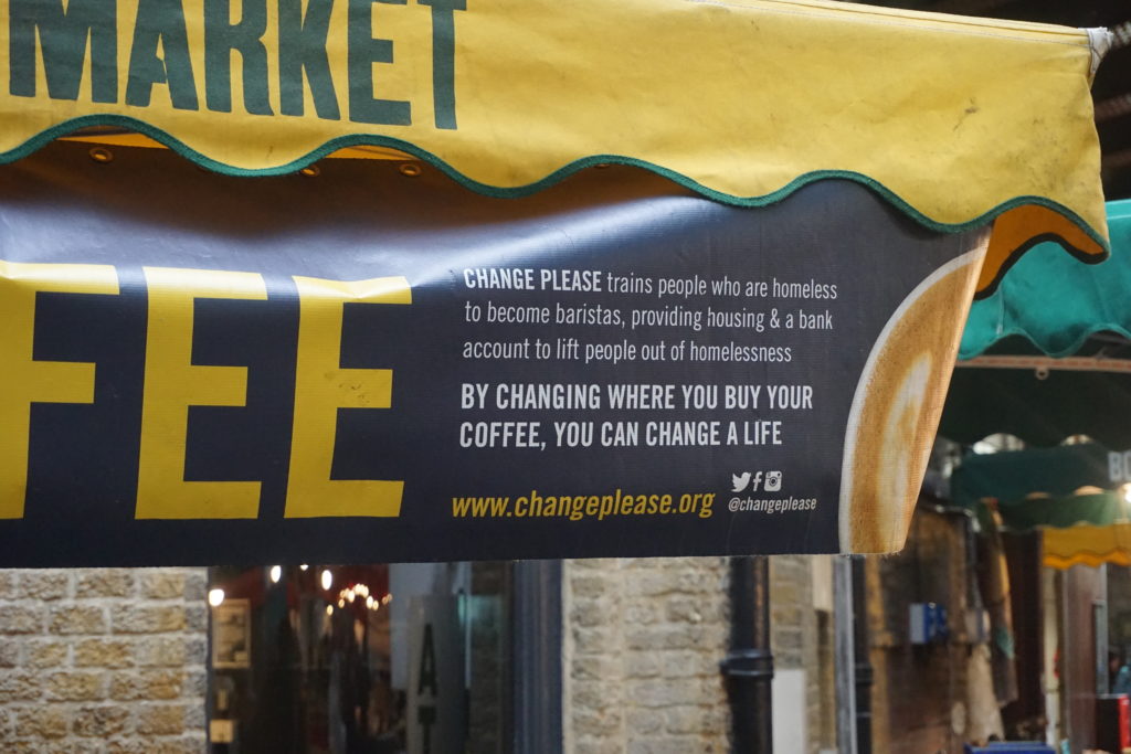 Change Please Coffee stand, it reads Change Please trains people who are homeless to become baristas, providing housing and a bank account to lift people out of homelessness
