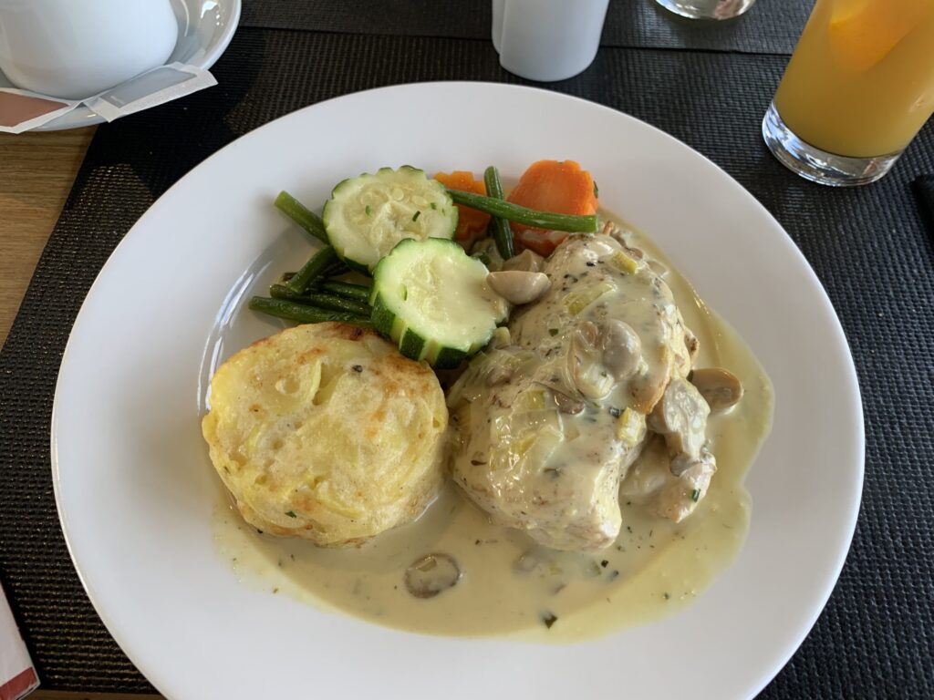 A white plate with chicken breast and a creamy mushroom sauce.