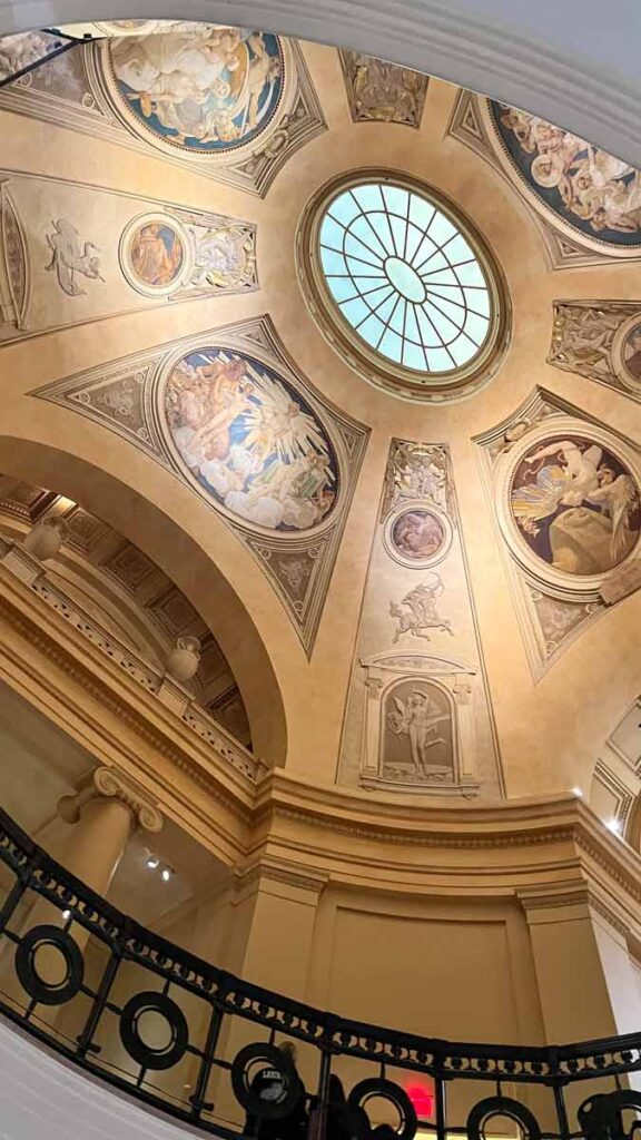 A photo of a cupola painted with religious motifs. The top is a circle made of glass.