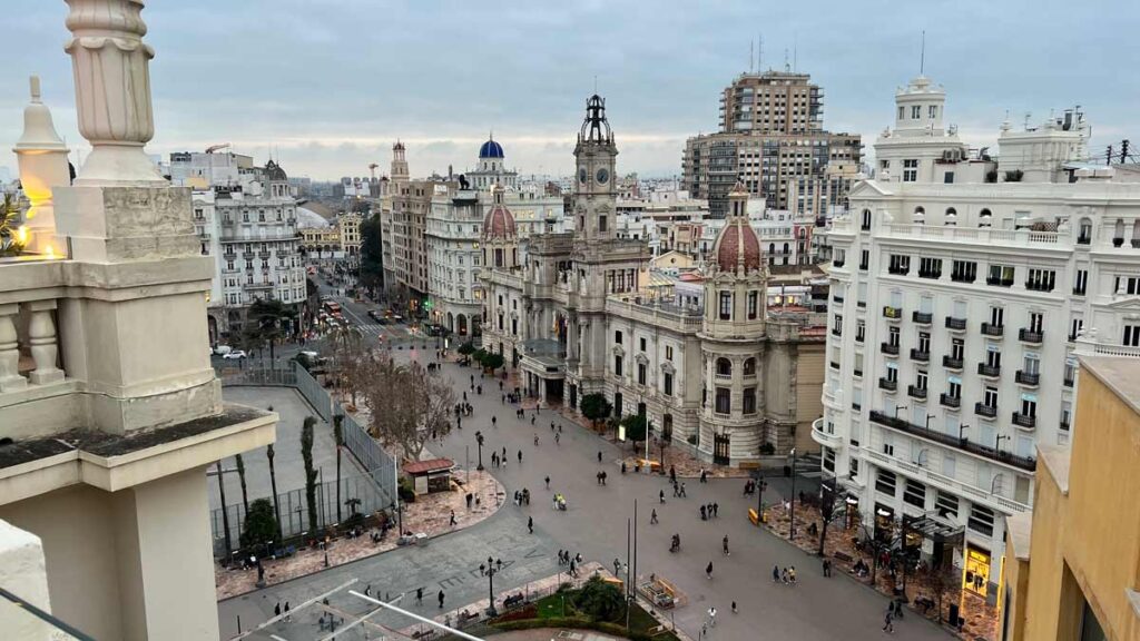 A photo of a pedestrian street in Valencia, taken from a rooftop terrace. You can see the typical Spanish architecture among gothic churches with tall towers.
