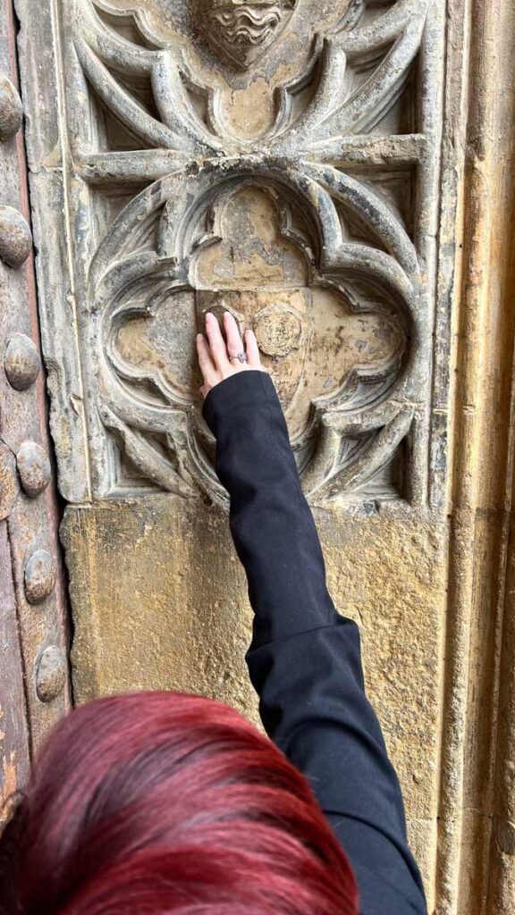 A close-up of Sassy's hand touching a medieval ornament on a building.