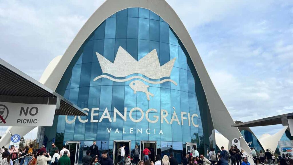 The entrance to the Oceanografic, which is made of glass and looks like a massive wave. It is a cloudy day.